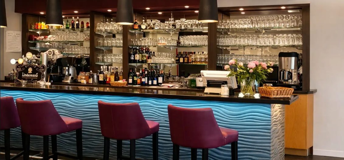 Agencement d’un espace accueil en maison de retraite avec mobilier sur mesure en bois, mur végétal stabilisé et meuble de tri du courrier.