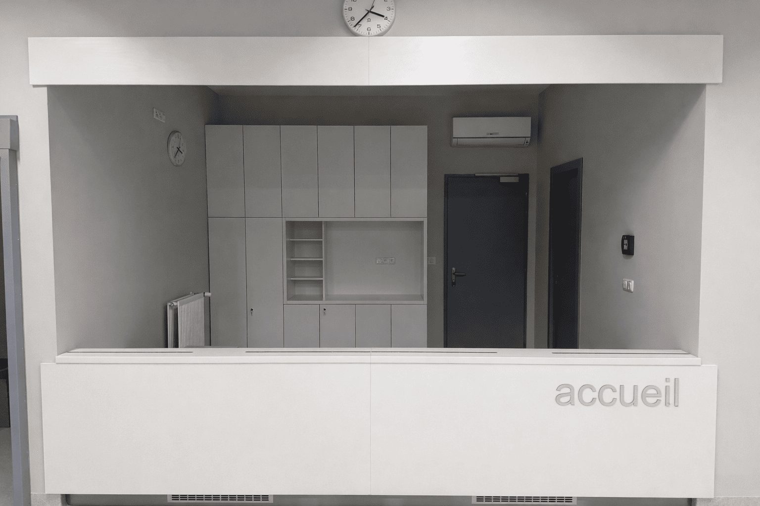 Banque d’accueil moderne blanche avec rangements intégrés dans un espace professionnel épuré